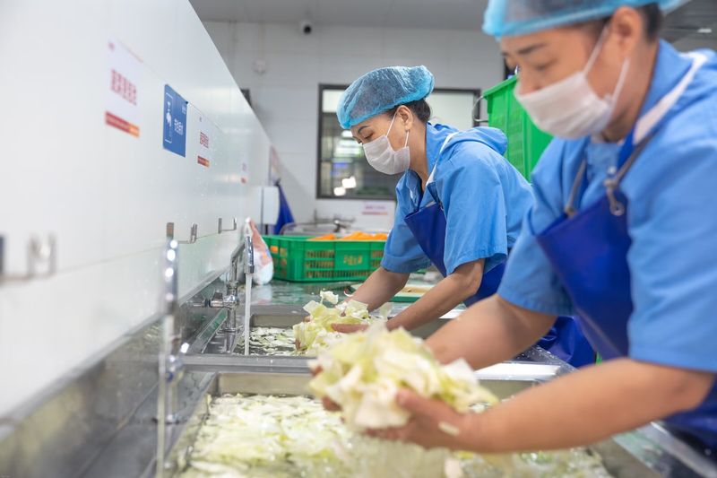 蔬菜清洗区，工作人员在清洗池中清洗包菜