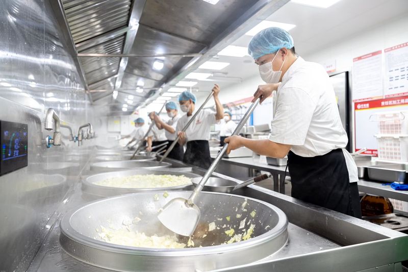 热链烹饪区,厨师团队在大锅前翻炒菜品蒸汽弥漫