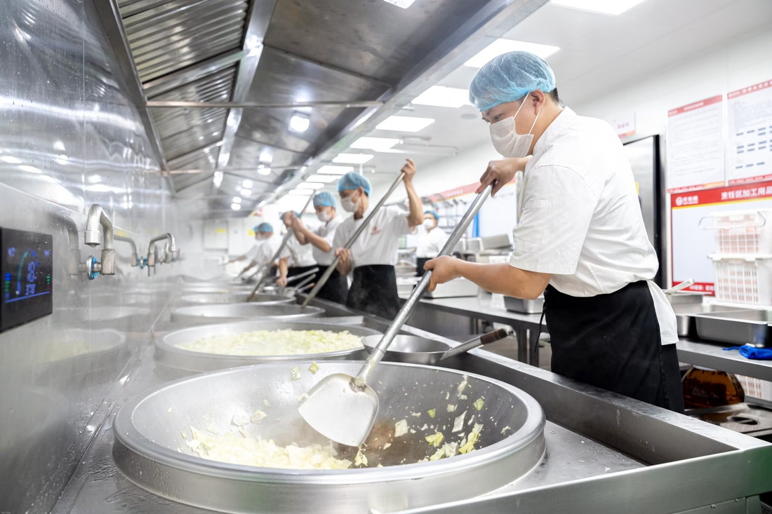 热链烹饪区,厨师团队在大锅前翻炒菜品蒸汽弥漫