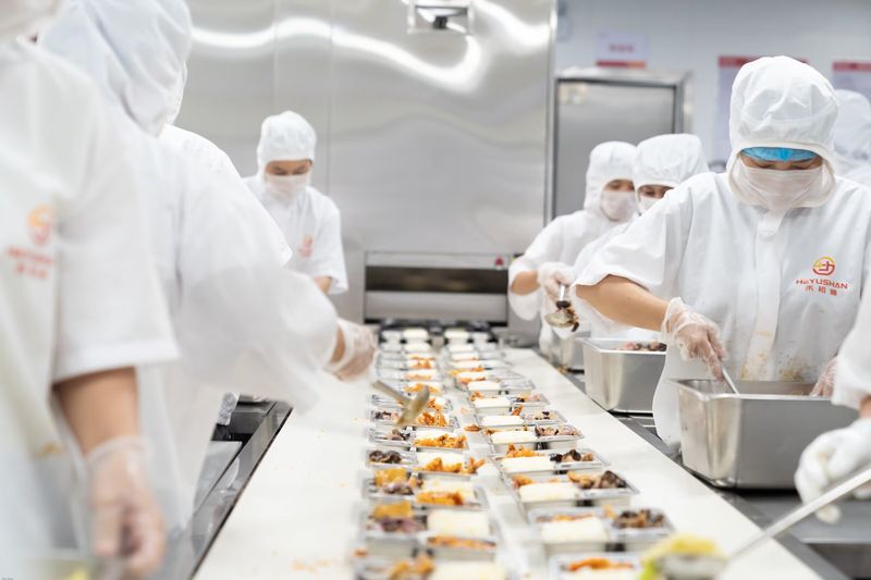 分餐装盒作业，工作人员往四格餐盒中精准打菜