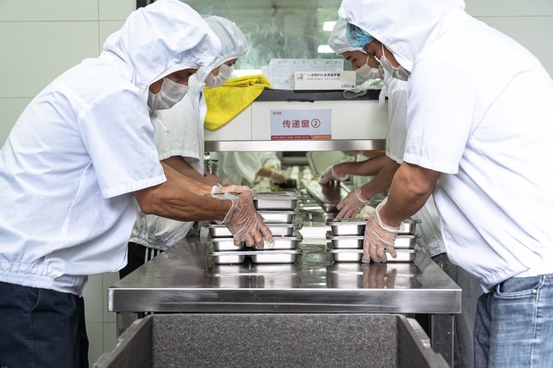 传递窗出餐口,工作人员通过传递窗传递装好的餐盒