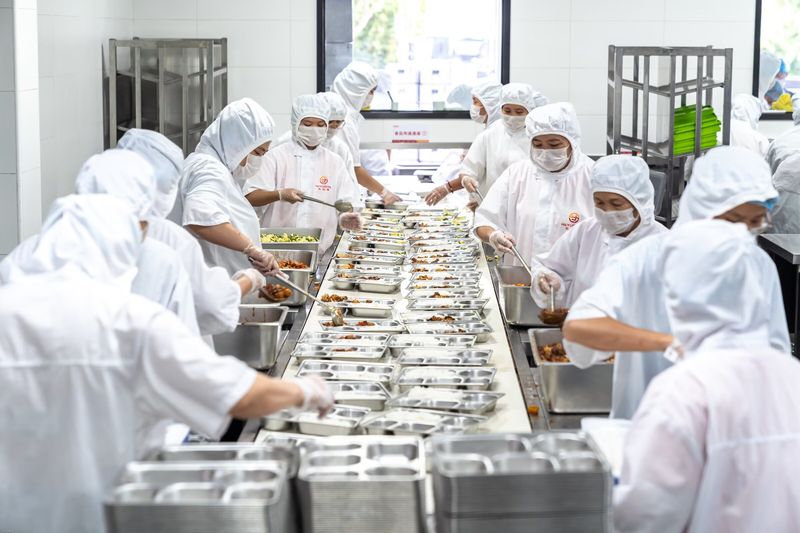 分餐流水线长景，传送带上餐盒依次经过各菜品档口