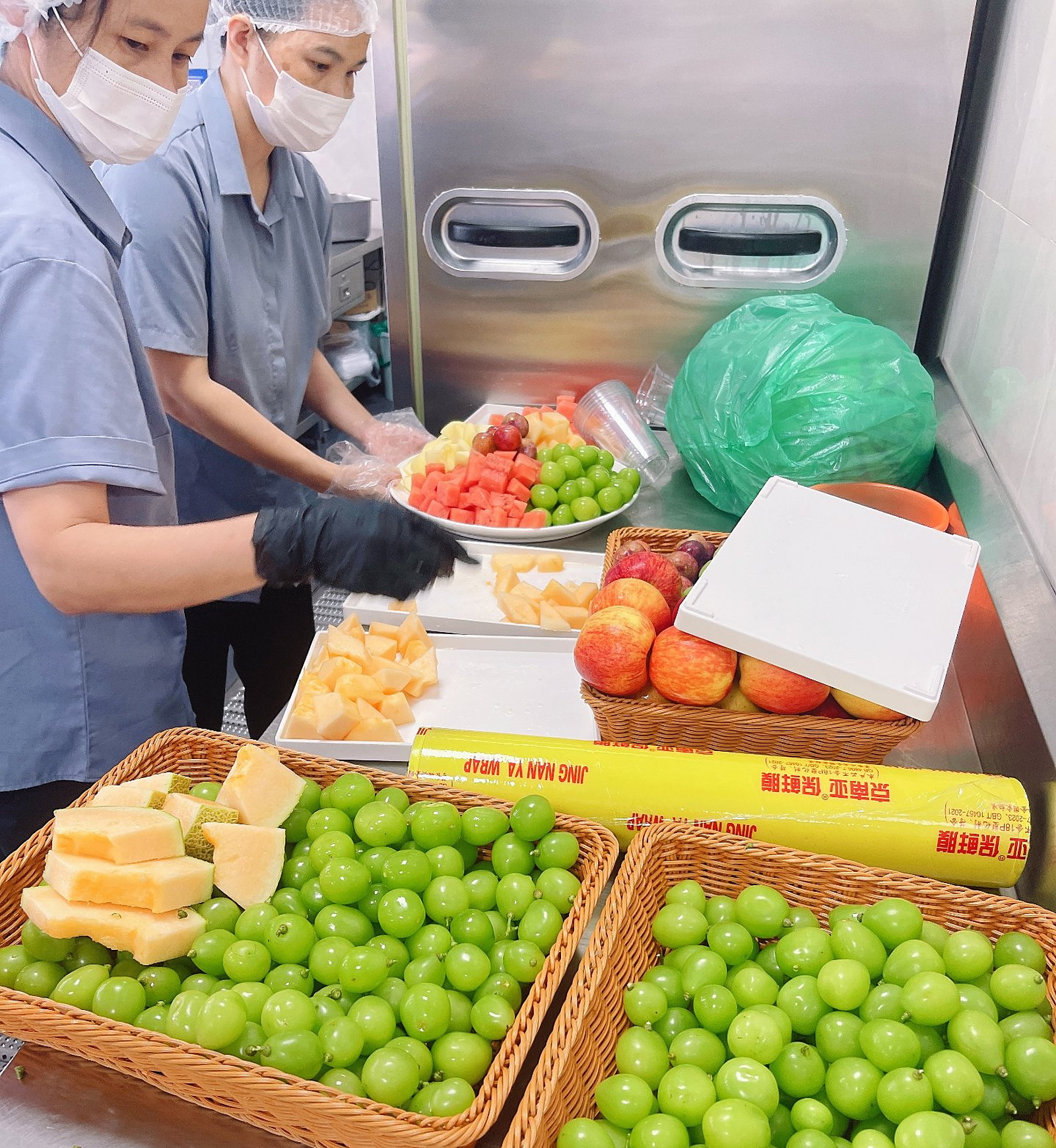 供餐后厨现场：青提、哈密瓜、西瓜、菠萝现切装盘分装